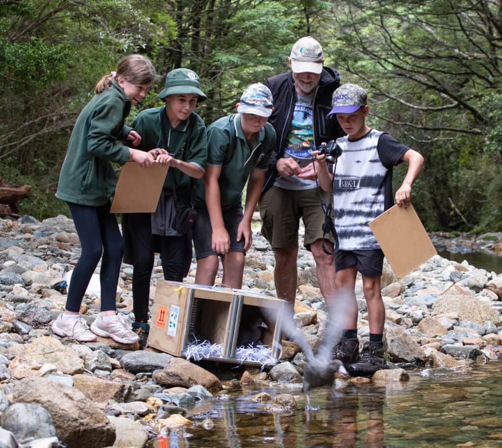 a group of people standing on rocks by a river with boxes